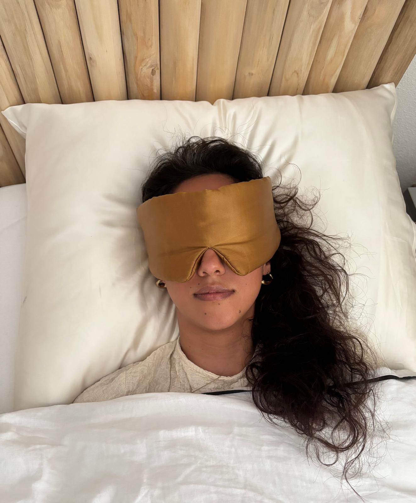 Vrouw met goudkleurig zijden slaapmasker slapend op ivoorkleurig kussen – natuurlijk zelfzorgmoment van Empowherment
